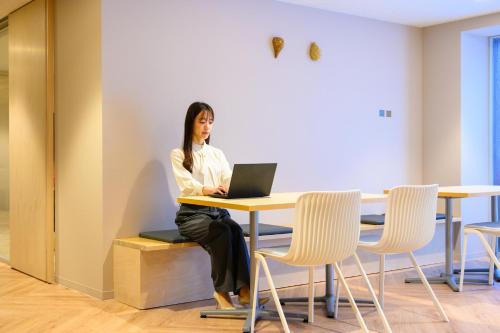a woman sitting at a table with a laptop at hotel miura kaen in Takikawa