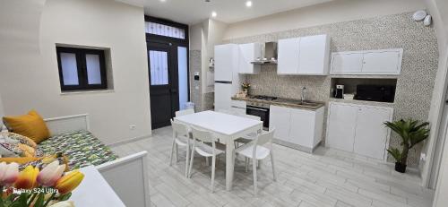 eine Küche und ein Wohnzimmer mit einem weißen Tisch und Stühlen in der Unterkunft Gesuiti Home di Agata e Aurora in Catania