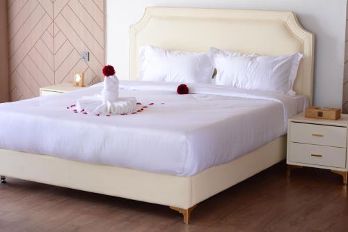 ein Schlafzimmer mit einem weißen Bett mit zwei Rosen darauf in der Unterkunft THE ARK PARADIO LODGE in Naivasha