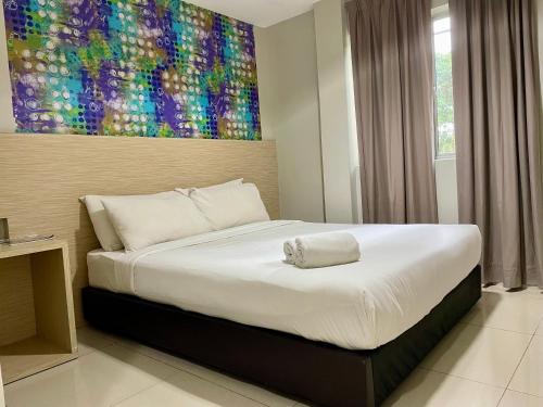 Living At DSulaiman Hotel في كوالالمبور: غرفة نوم بسرير كبير عليها لوحة على الحائط