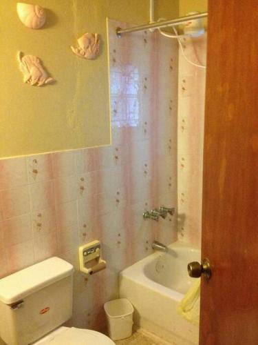 a bathroom with a toilet and a bath tub at Boothe's Palace in Oracabessa