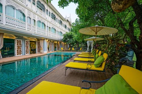 a swimming pool with yellow lounge chairs and an umbrella at At Pingnakorn Riverside in Chiang Mai