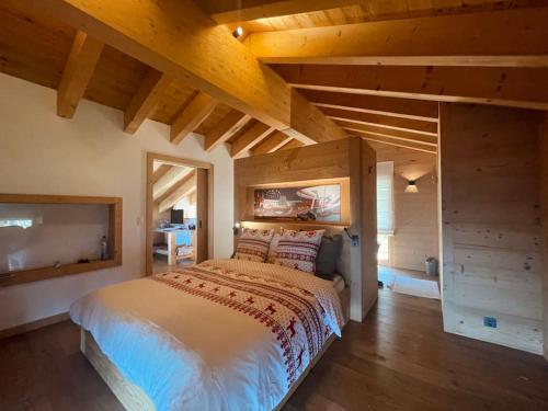 a bedroom with a large bed and wooden ceilings at Chalet VG stunning view, Sauna & Jacuzzi by Jolidi in Nendaz