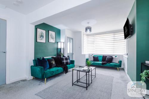 a living room with two green couches and a table at Emerald House, Manchester - by Synergy Estates in Manchester