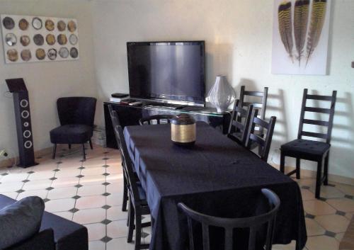 uma sala de jantar com uma mesa e cadeiras e uma televisão em Grande maison à louer à La Londe les maures em La Londe-les-Maures