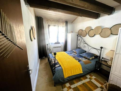 - une chambre avec un lit doté d'une couverture jaune et d'oreillers bleus dans l'établissement Au pied des Remparts 10 rue Saint jean, à Villefranche-de-Conflent
