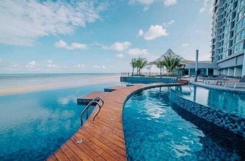 una piscina junto a una playa y un edificio en Gothca Imperium Residence Kuantan Studio Seaview, en Kuantan