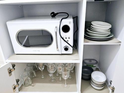 a white microwave sitting on a shelf with wine glasses at Stay Popo in Seoul