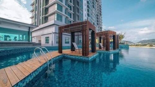 a swimming pool in front of a building with water at Leisure Imperium Residence Studio Seaview Kuantan in Kuantan
