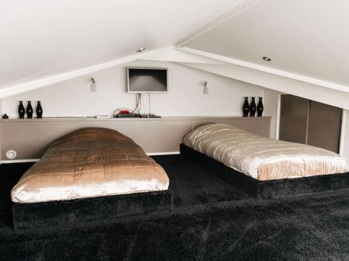 two beds in a room with a tv on the wall at Holiday home Satijnduiker in Makkum