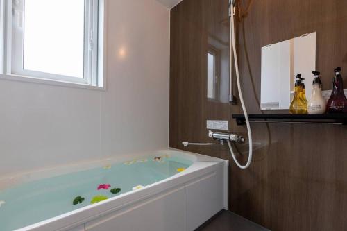 a bath tub in a bathroom with a window at 駐車場にコインランドリー畳部屋にお布団も敷けます最上階4階Room in Tomari