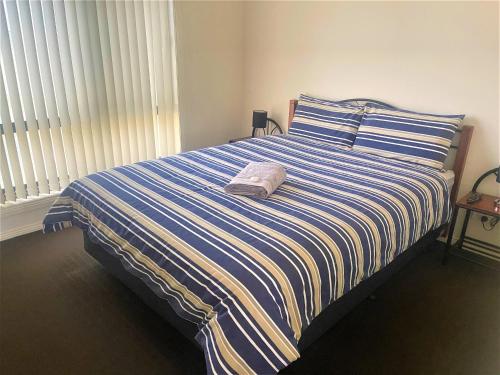 a bed with a blue and white striped comforter at DBJ Holiday Units in Mulwala