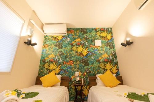 two beds in a room with a colorful wall at 駐車場にコインランドリー畳部屋にお布団も敷けます最上階4階Room in Tomari