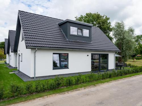 una casa blanca con techo negro en Beautiful holiday home with lots of space in a holiday park near Alkmaar, en Hensbroek