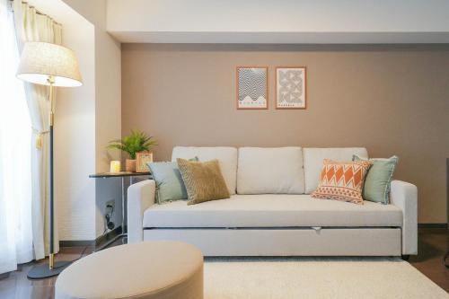 a living room with a white couch with pillows at Sun Court Odori Inn in Ōdōri