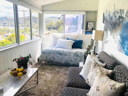 a living room with a bed and a couch and windows at Brisbane waters cottage at Point Clare NSW in Point Clare