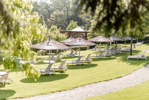 eine Gruppe von Stühlen und Sonnenschirmen auf dem Rasen in der Unterkunft Avita Resort Bad Tatzmannsdorf in Bad Tatzmannsdorf