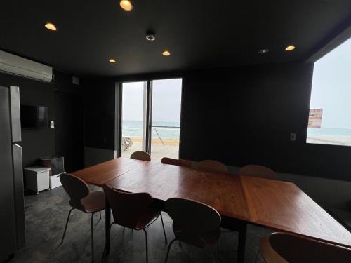 a conference room with a wooden table and chairs at ゲストハウス＆カフェ　ハレテル in Masuda