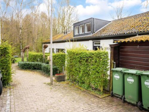 a house with two green trash cans in front of a driveway at Serene Holiday Home in Ulestraten with Terrace in Ulestraten