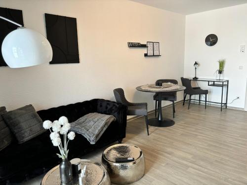ein Wohnzimmer mit einem schwarzen Sofa und einem Tisch in der Unterkunft Charming Homes - Studio 23 in Wolfsburg