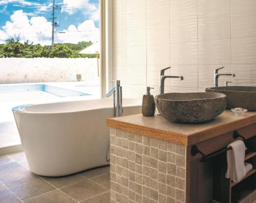 Fukai的住宿－コーラルテラス石垣島，浴室配有两个盥洗盆和浴缸。