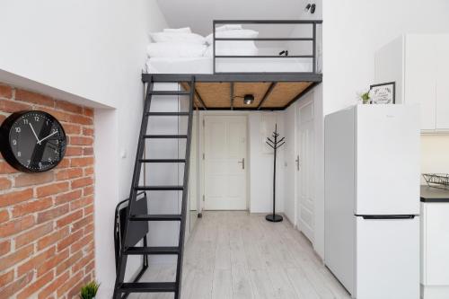 a room with a loft bed and a clock at Comfortable and Elegant Studio with Balcony for 4 People in Cracow by Renters in Krakow