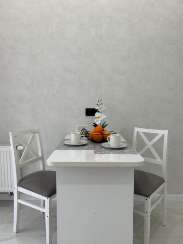 a white kitchen island with two chairs and a table with two cups at 1-комнатная возле Посольства США и Мечети Хазрет Султан in Astana