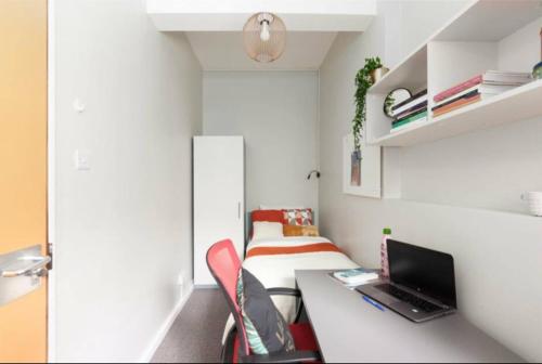 Habitación pequeña con escritorio y ordenador portátil. en Private room in rental unit, en Londres
