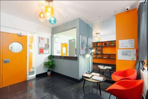 a room with orange walls and a table and chairs at Private room in rental unit in London