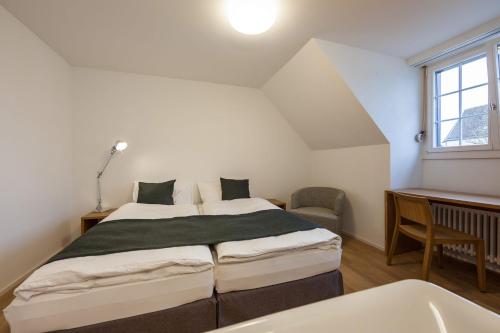 um quarto com uma cama, uma secretária e uma janela em Gasthof Oxen em Küsnacht