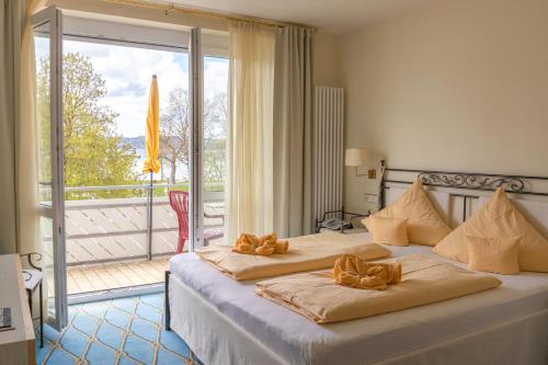 a bedroom with two beds and a balcony at Hotel & Restaurant Mainaublick in Uhldingen-Mühlhofen