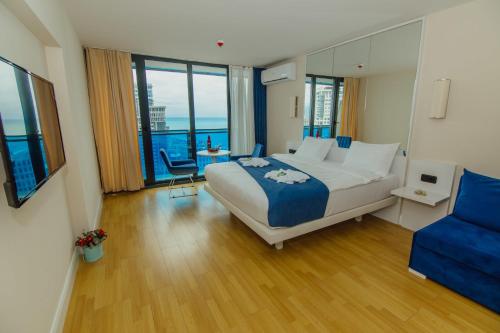 um quarto com uma cama grande e uma cadeira azul em Orbi City Hotel Batumi Beach em Batumi