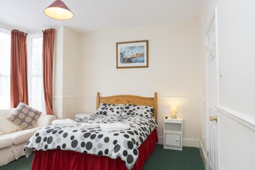 a bedroom with a black and white bed and a couch at Southend Guest House - Close to Beach, Train Station & Southend Airport in Southend-on-Sea