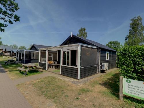 a small cabin with a picnic table in front of it at Cozy tentlodge with roofed terrace in a green area in IJhorst