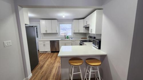 a kitchen with white cabinets and two bar stools at St B. Living in Winnipeg