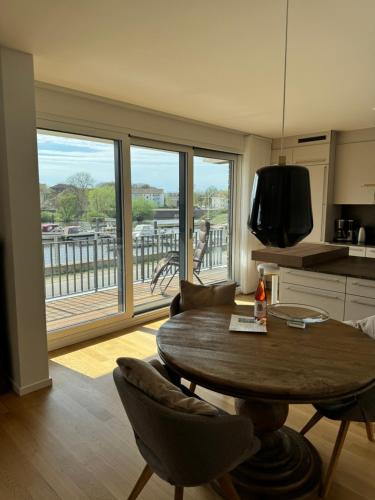 a living room with a table and a kitchen with a balcony at Allerinsel - Appartement am Celler Yachthafen in Celle