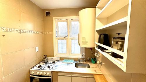 a small kitchen with a sink and a stove at Cálido dpto de 2 ambientes con parrilla y cochera en zona residencial de Punta Mogotes in Mar del Plata