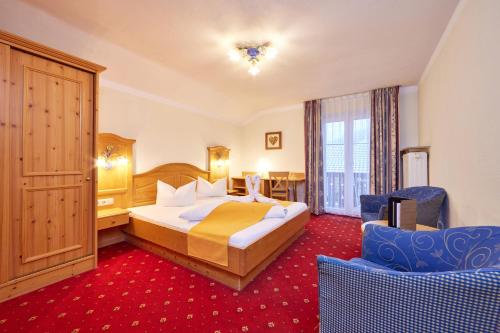 a hotel room with a bed and two chairs at Alpenhotel Rieger in Mittenwald