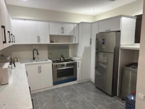 a kitchen with white cabinets and a stainless steel refrigerator at شقة غرفتين وصاله وغرفة خادمة او سائق in Riyadh