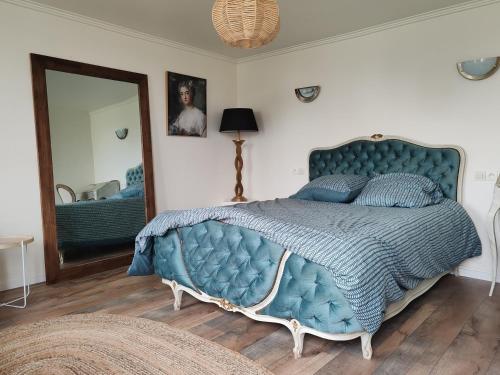 1 dormitorio con cama azul y espejo en Golf&Love in Normandy, en Sainte-Opportune-du-Bosc