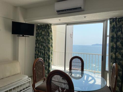 a living room with a glass table and a balcony at Hermosa Suite en Acapulco in Acapulco