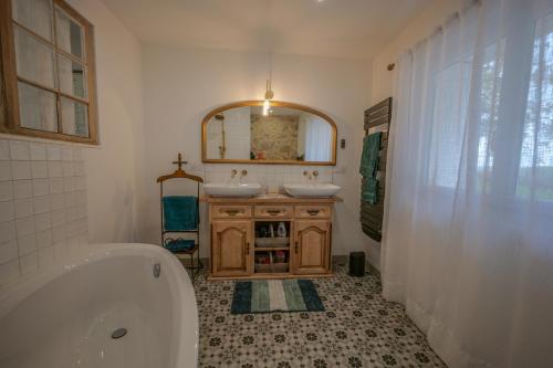 La salle de bains est pourvue d'une baignoire, de 2 lavabos et d'un miroir. dans l'établissement Le Balesté - Logement 1, à Montesquieu