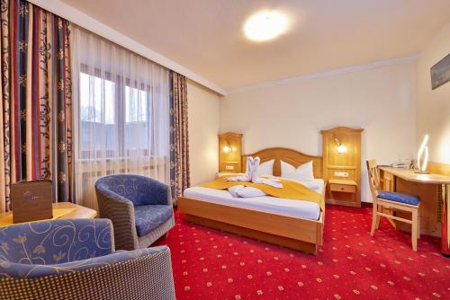 a hotel room with a bed and a desk at Alpenhotel Rieger in Mittenwald