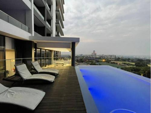 - Balcón de un edificio con sillas y piscina en 11th floor Lux queen room with great balcony view, en Johannesburgo