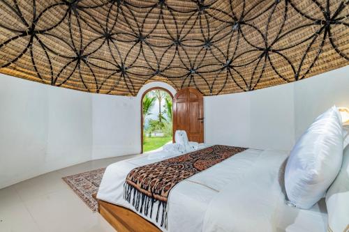 a bedroom with a large bed with a ceiling at Ritual Ubud in Gianyar