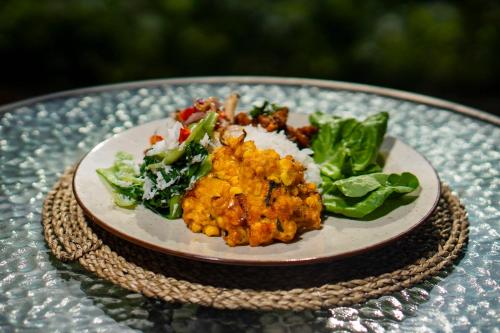 a plate of food with rice and greens on a table at Ritual Ubud in Gianyar