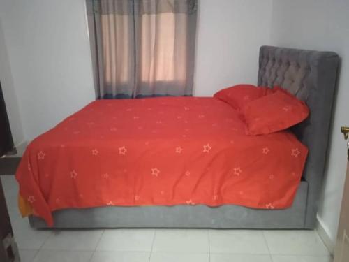 a bed with a red comforter and two pillows at 3 bedroom, free Wi-fi, Aircon & Hot water in Tujering