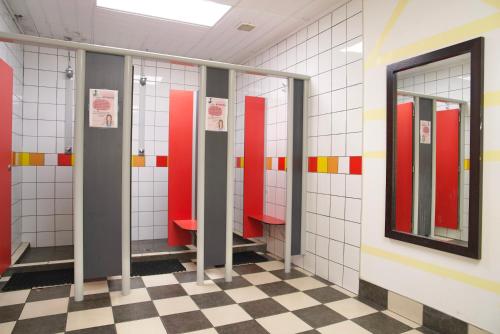 a row of stalls in a bathroom with red and white tiles at Silverfern Backpackers in Auckland