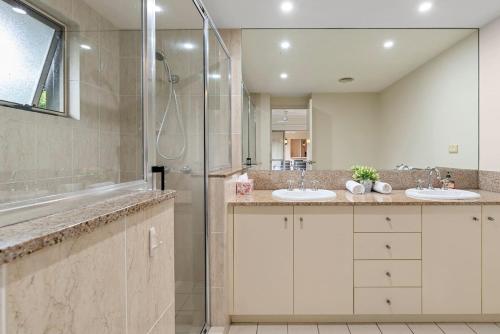 y baño con 2 lavabos y ducha. en Discover a Lush Poolside Stay at The Lakes Resort, en Cairns North