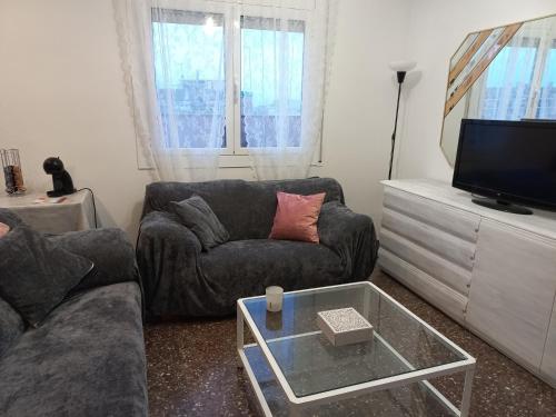 a living room with a couch and a tv at Cozy and sunny penthouse Fira BCN in Hospitalet de Llobregat